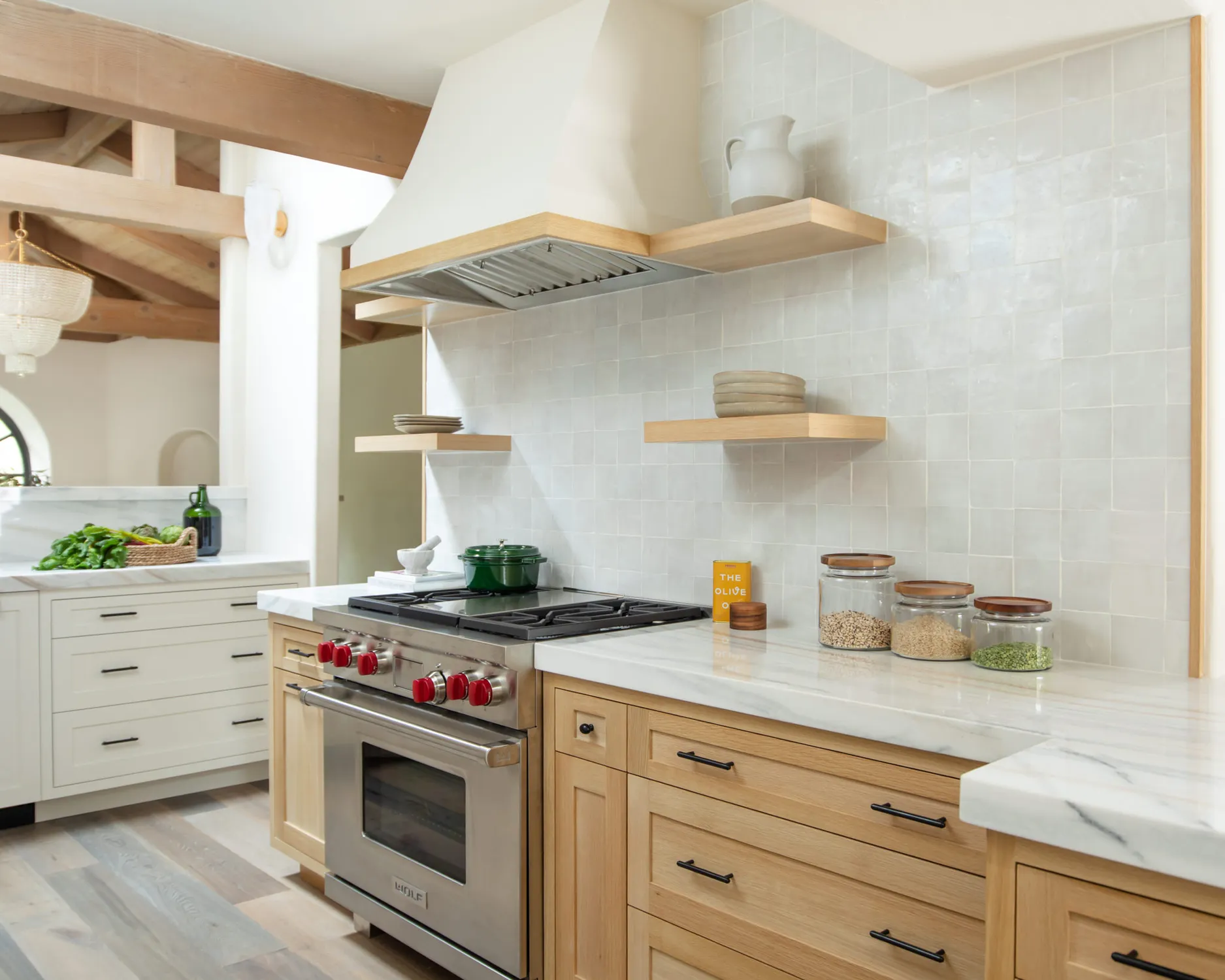 White kitchen range beneath a plaster hood and wood shelves