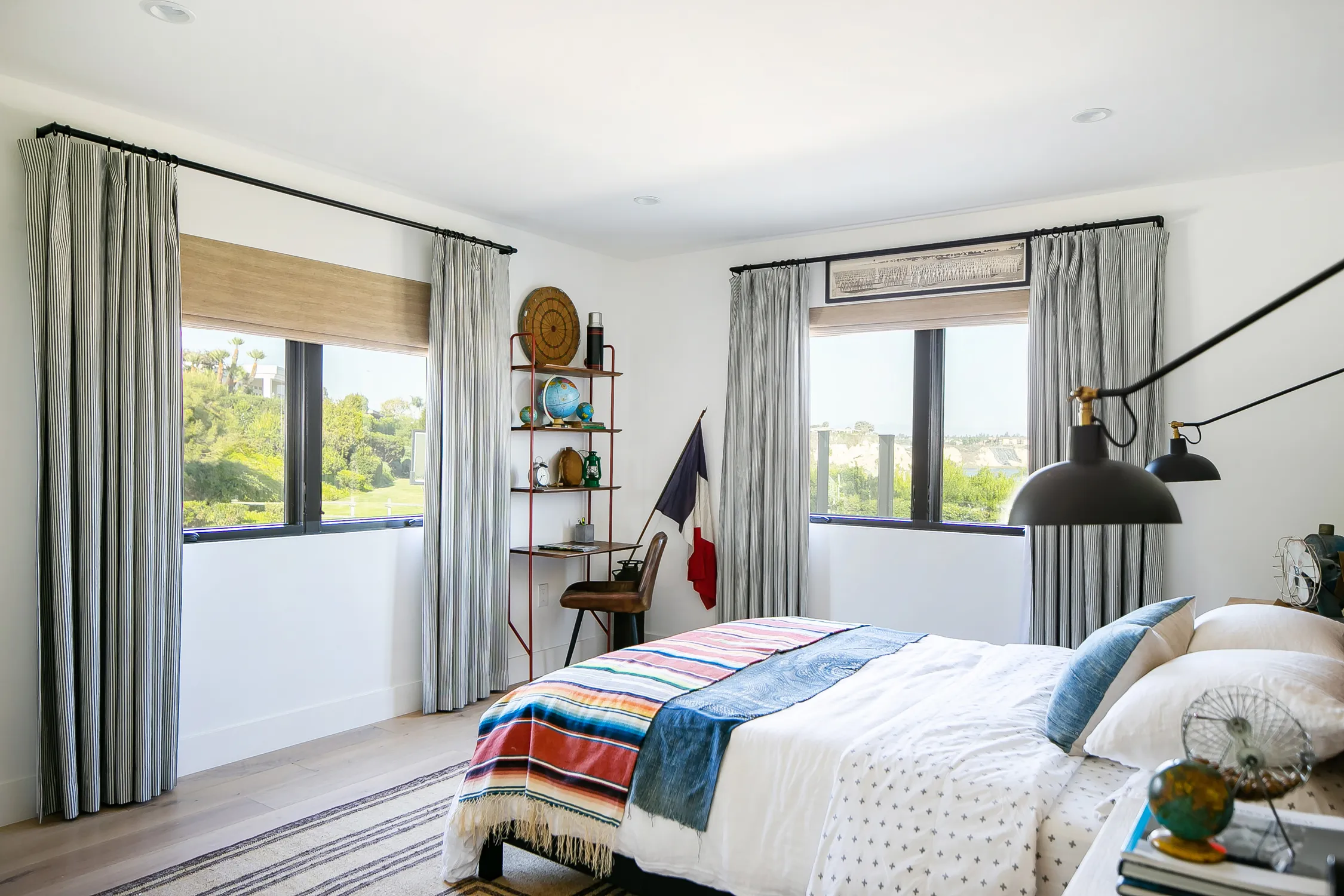 Bedroom with large black-framed window and striped bedding