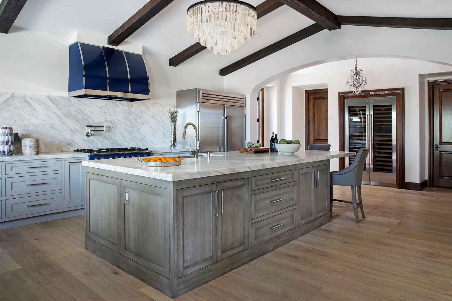 Gray kitchen with marble island and blue range hood