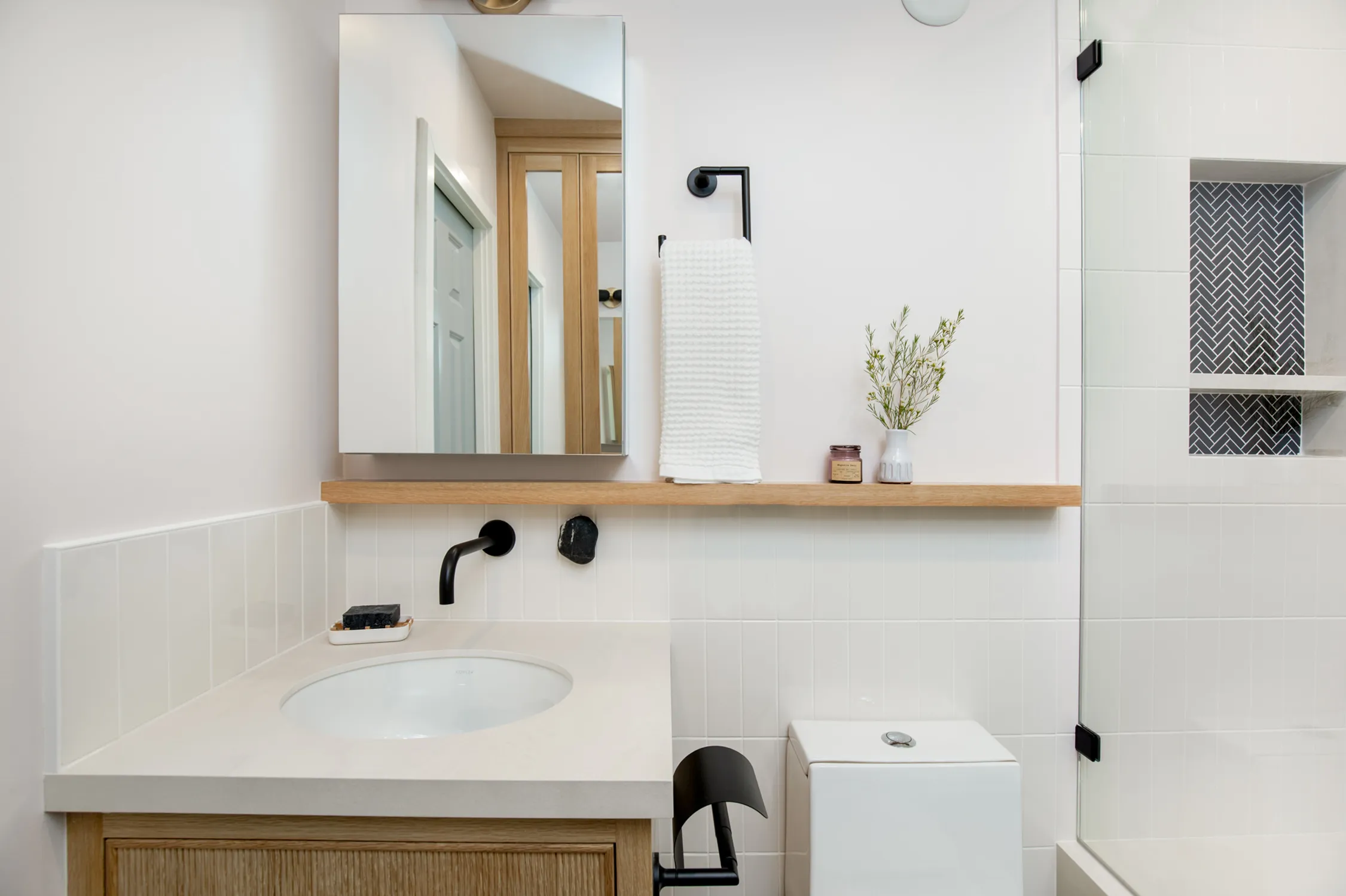 Compact white vanity with wood countertop and black faucet