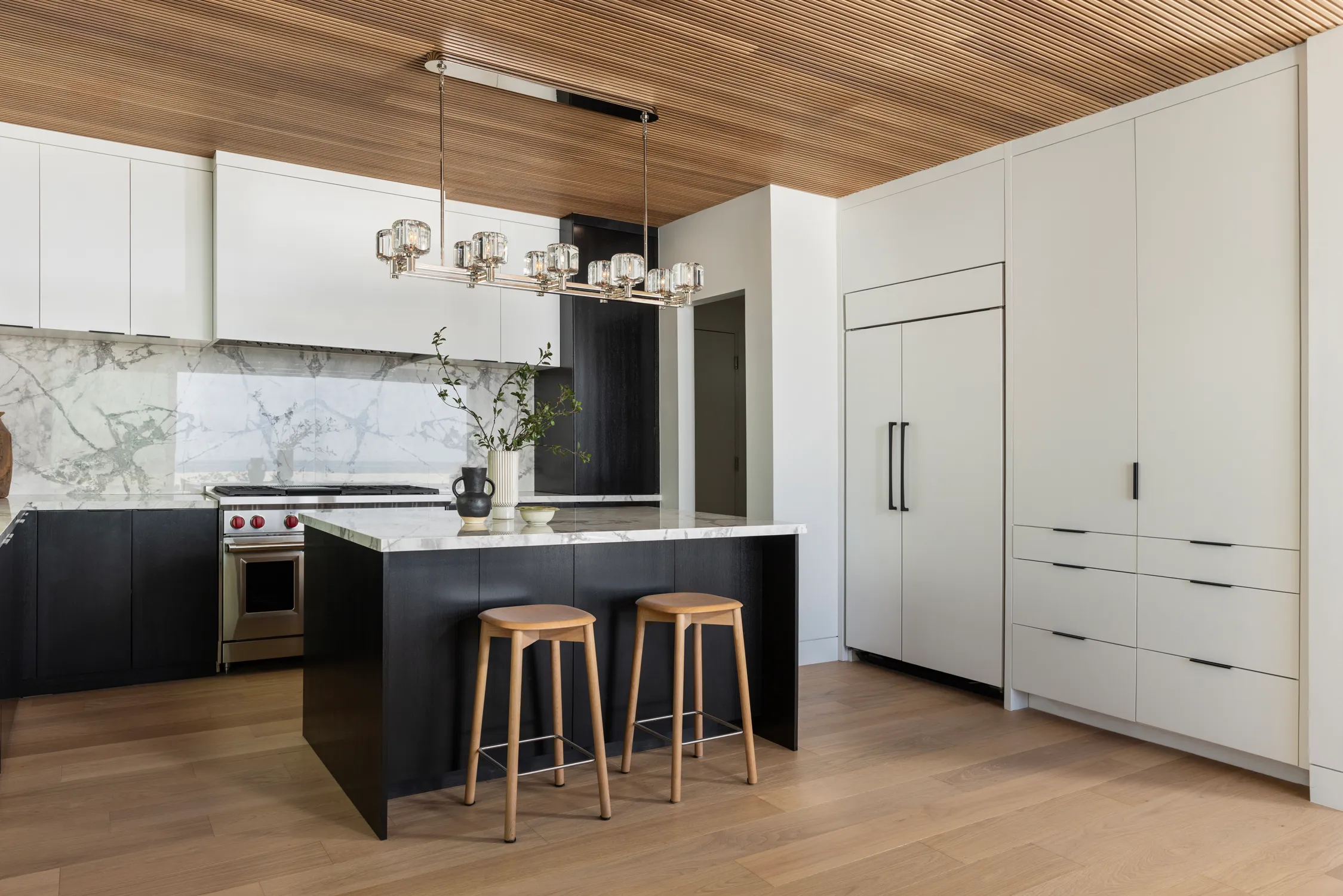 Kitchen with black island, white cabinets, and slatted wood ceiling
