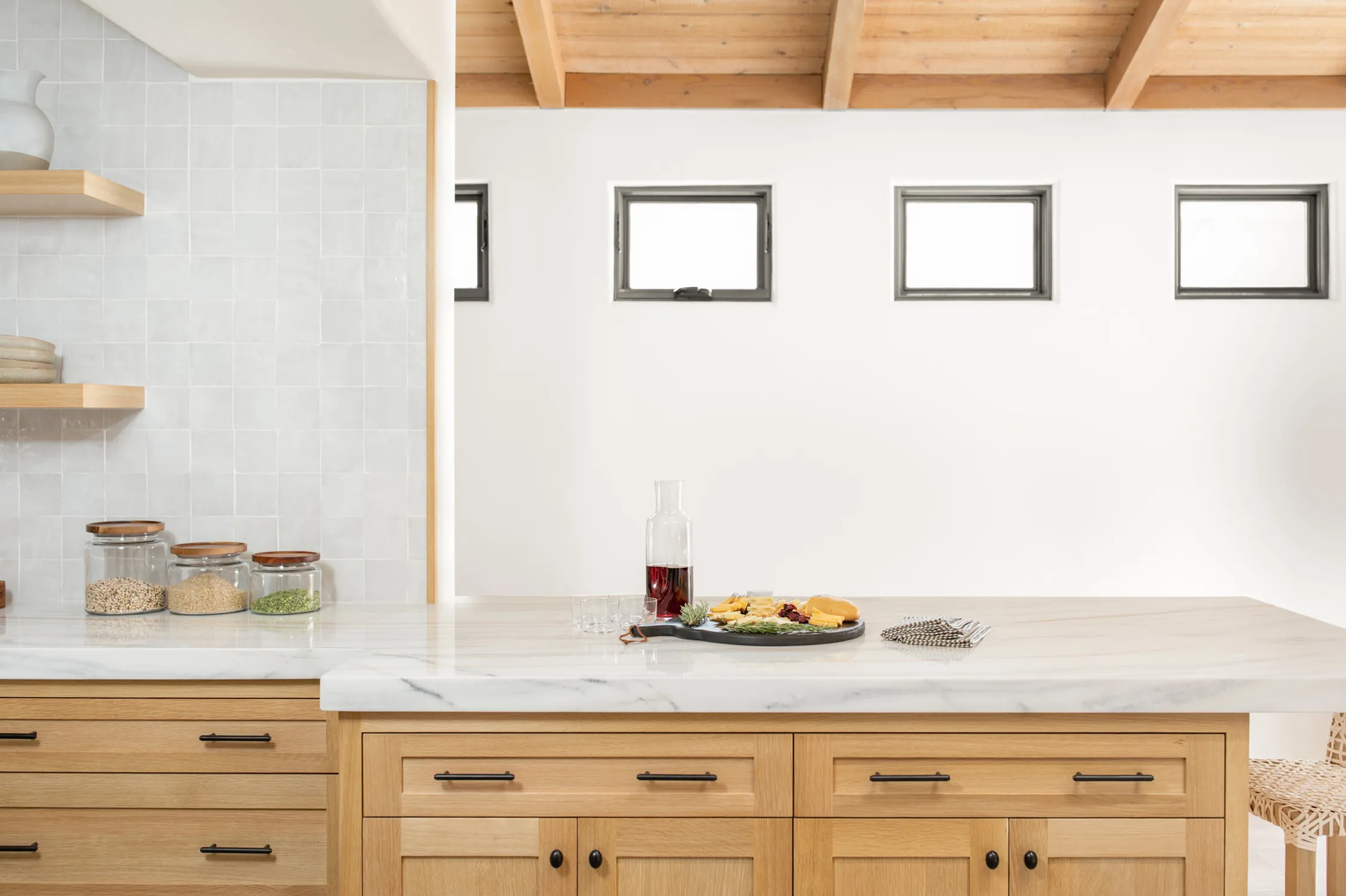 Light-wood kitchen cabinets below white subway tile