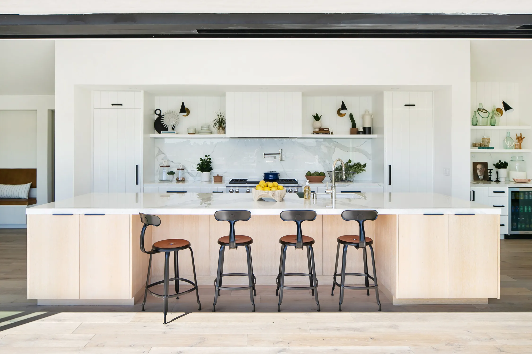 White kitchen with wood island and four black bar stools