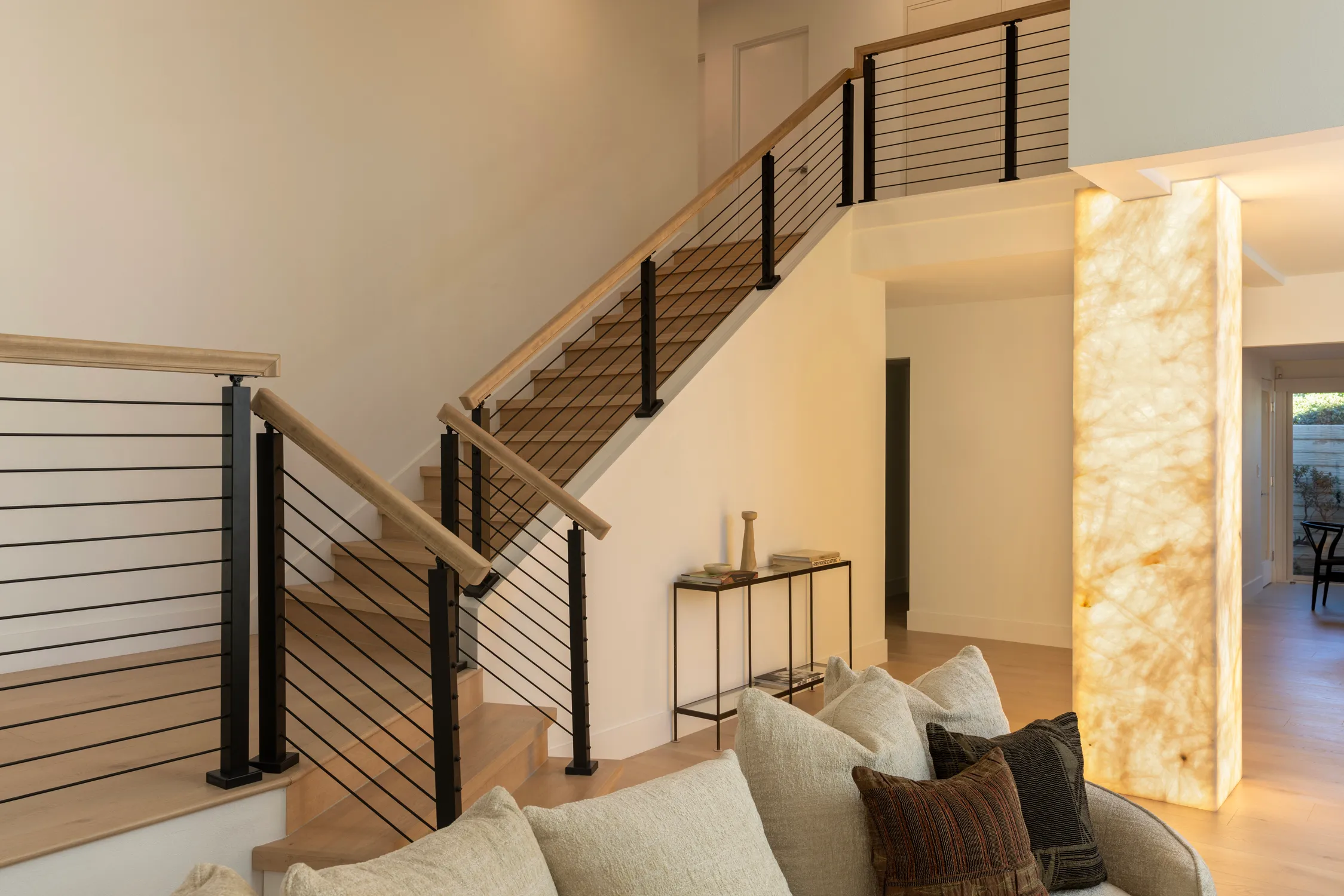 Open staircase with metal railing and illuminated stone wall