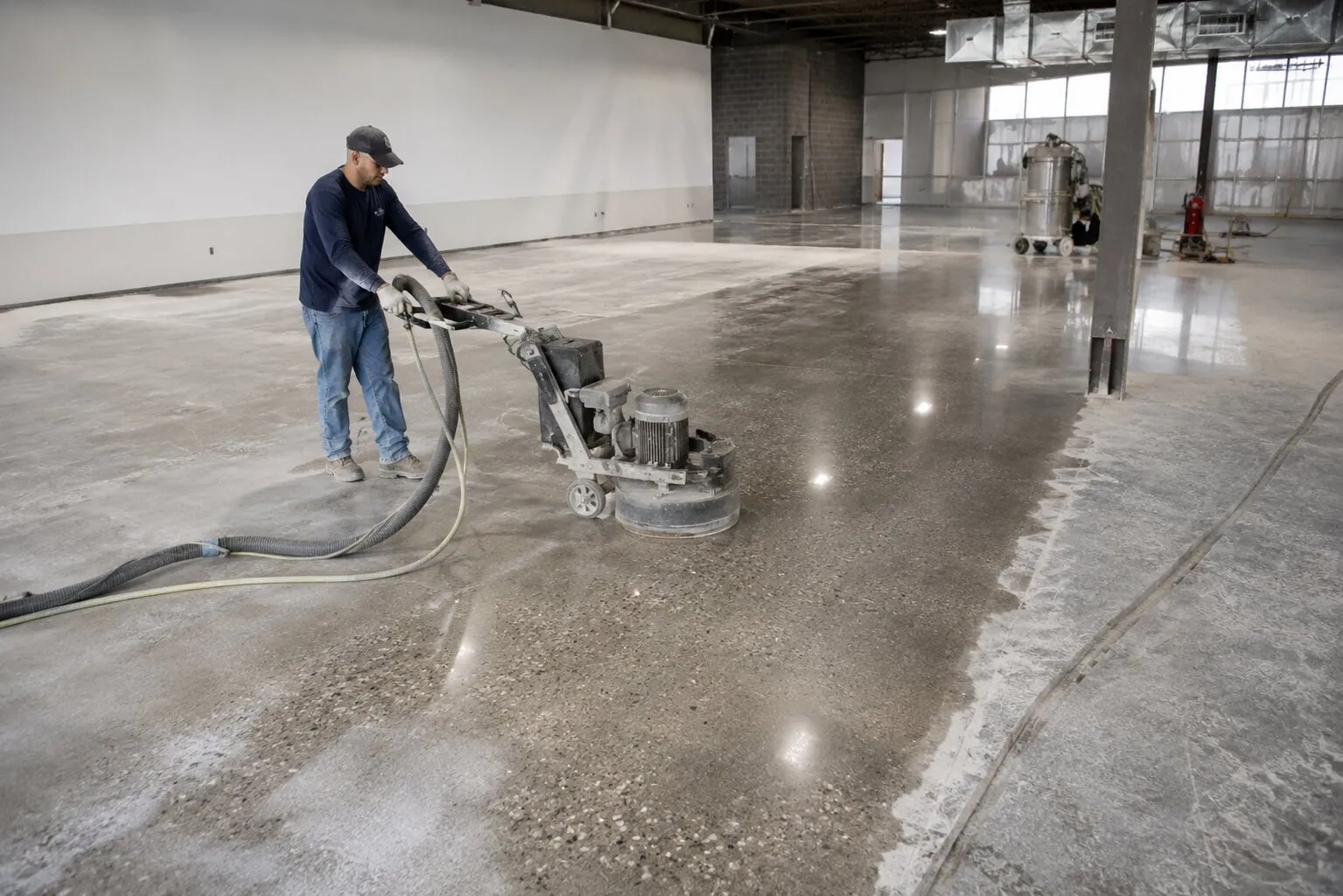 Worker grinding a concrete floor in a large open building