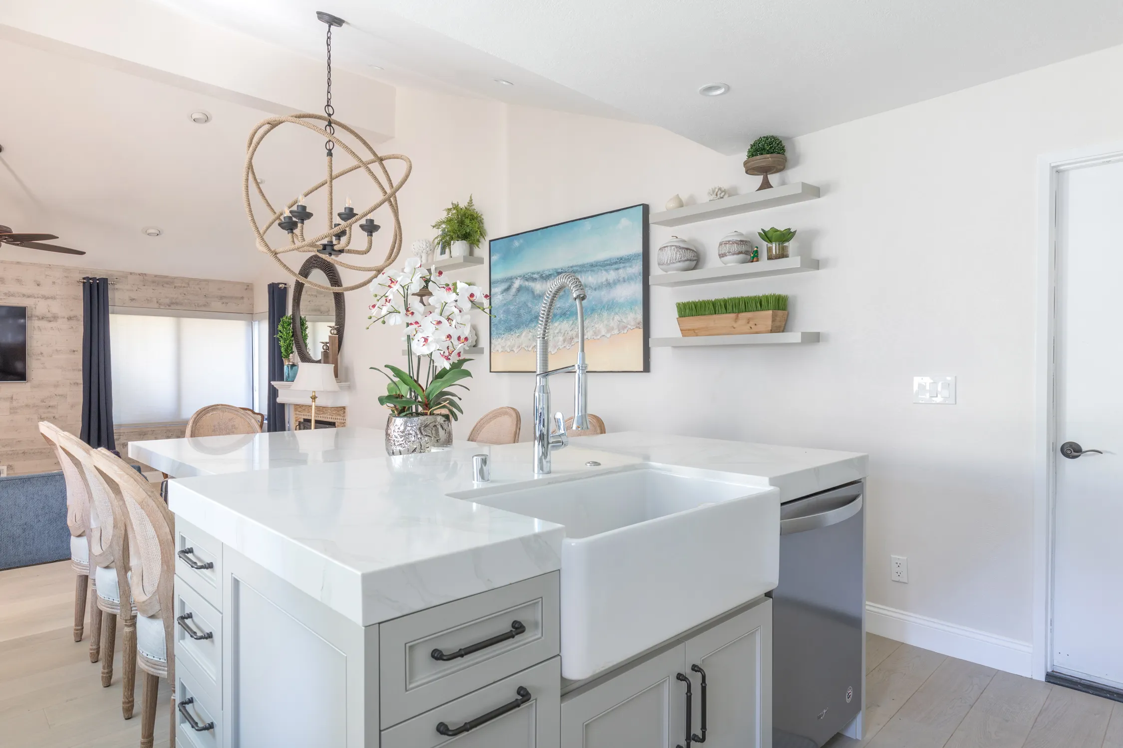 White kitchen island with globe chandelier and open dining area