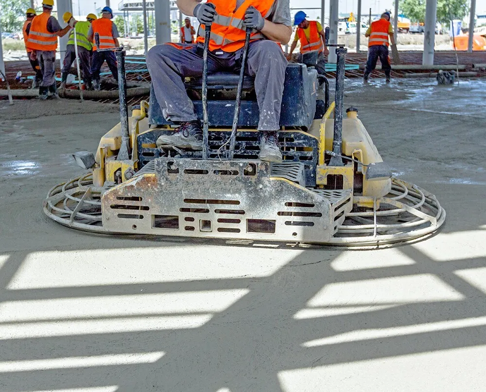 Worker operating a power trowel on a concrete slab