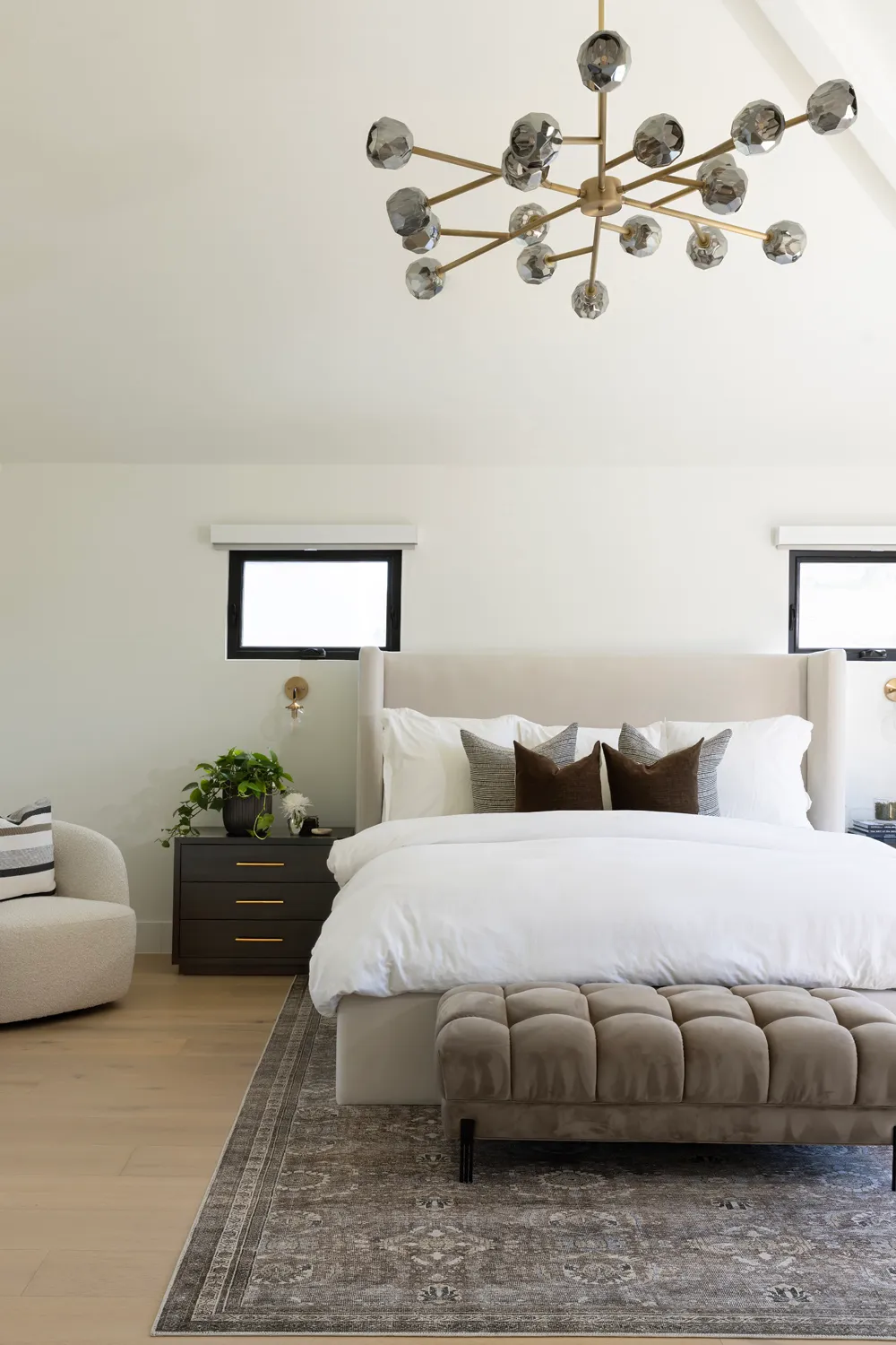 Primary bedroom beneath a sculptural brass chandelier.