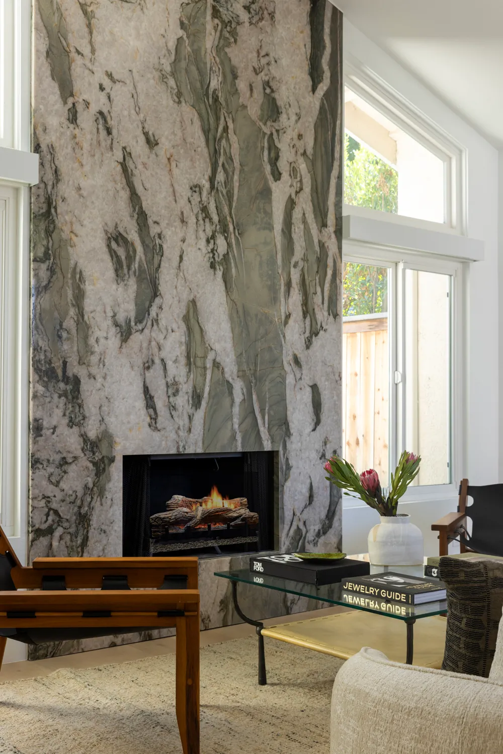 Living room with tall stone fireplace and large windows