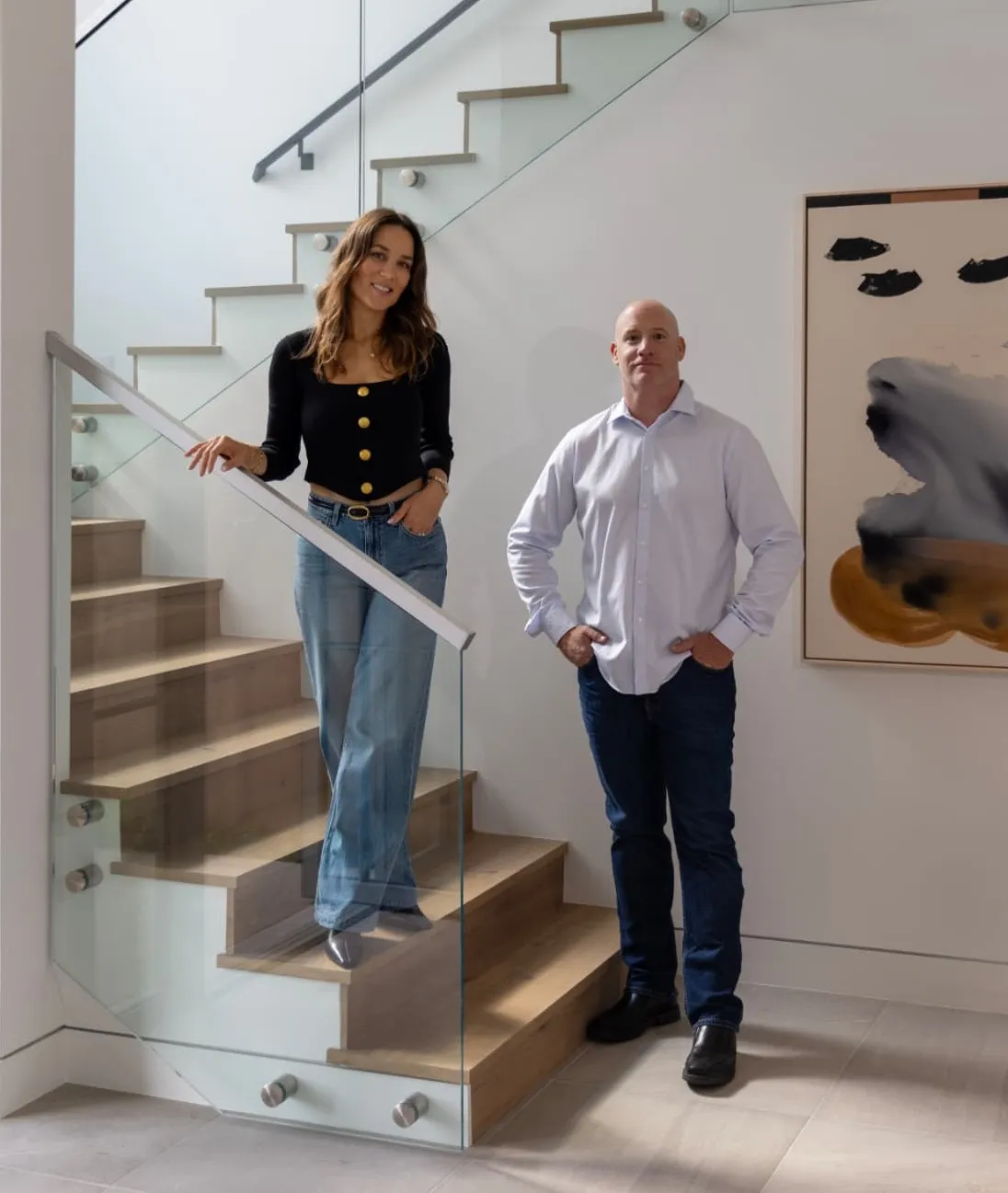 Michelle Yahav and Ami Gilad beside a glass-railed staircase