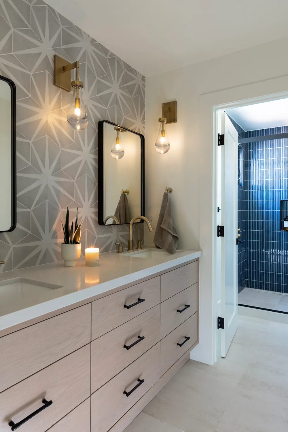 Bathroom vanity with geometric tile wall and blue tiled shower