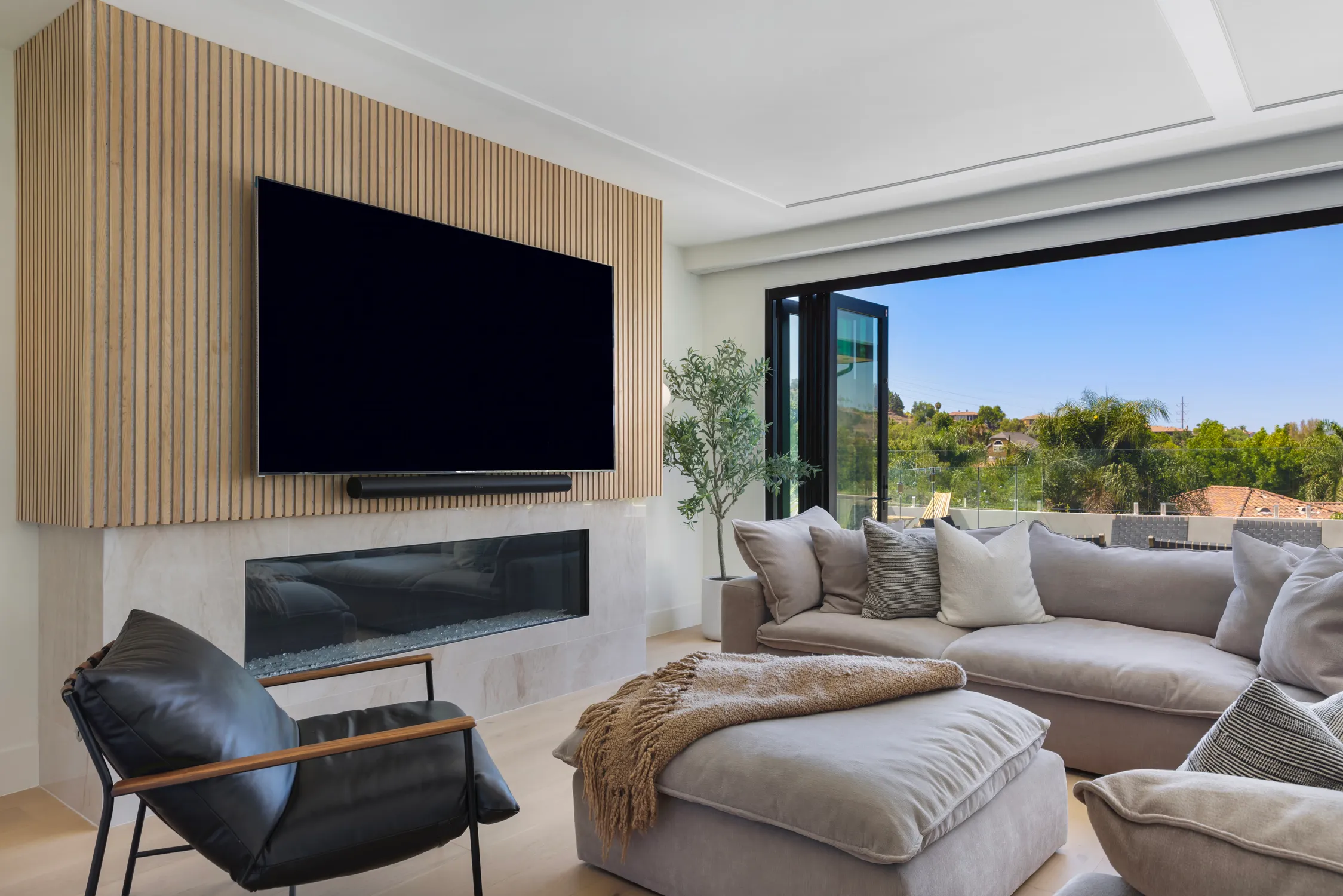 Living room with slatted fireplace wall and open folding glass doors