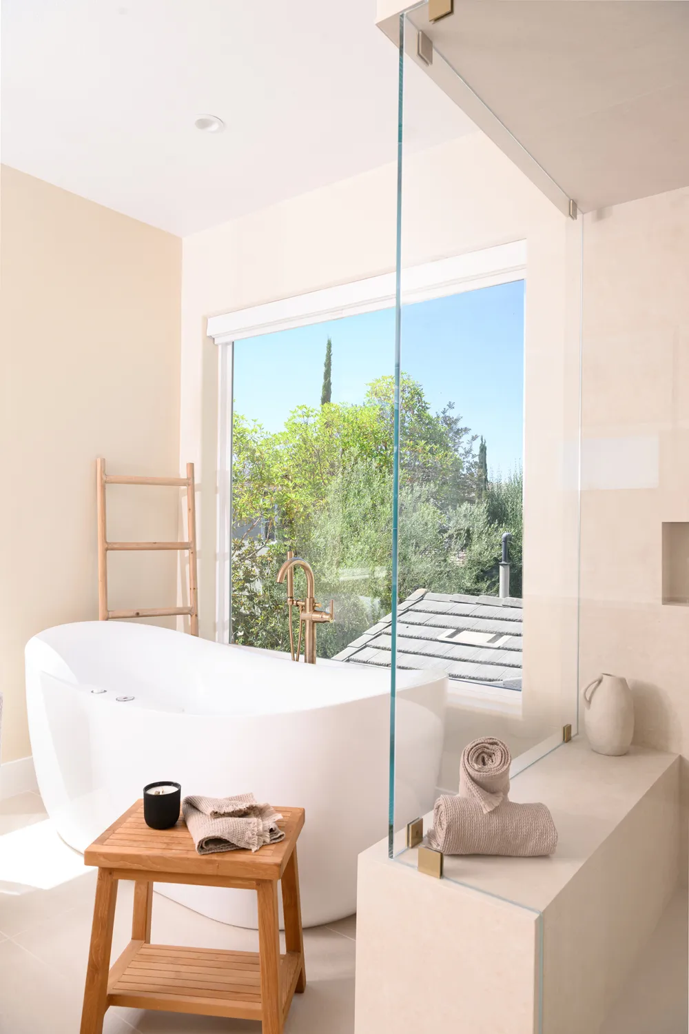 Freestanding bathtub beneath a large window
