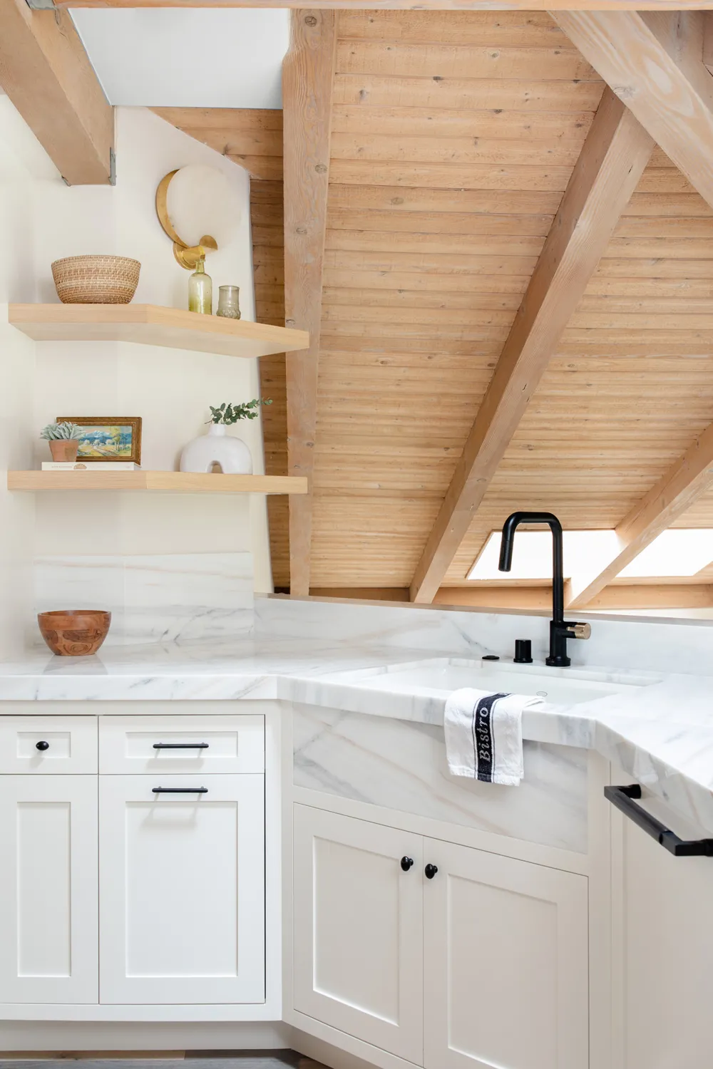 White kitchen sink below vaulted wood ceiling
