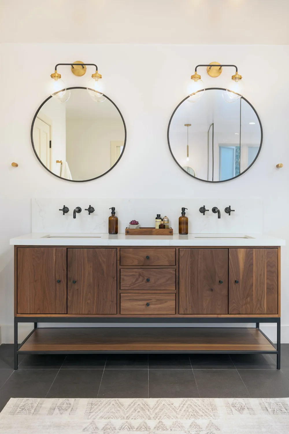 Wood double vanity beneath round mirrors