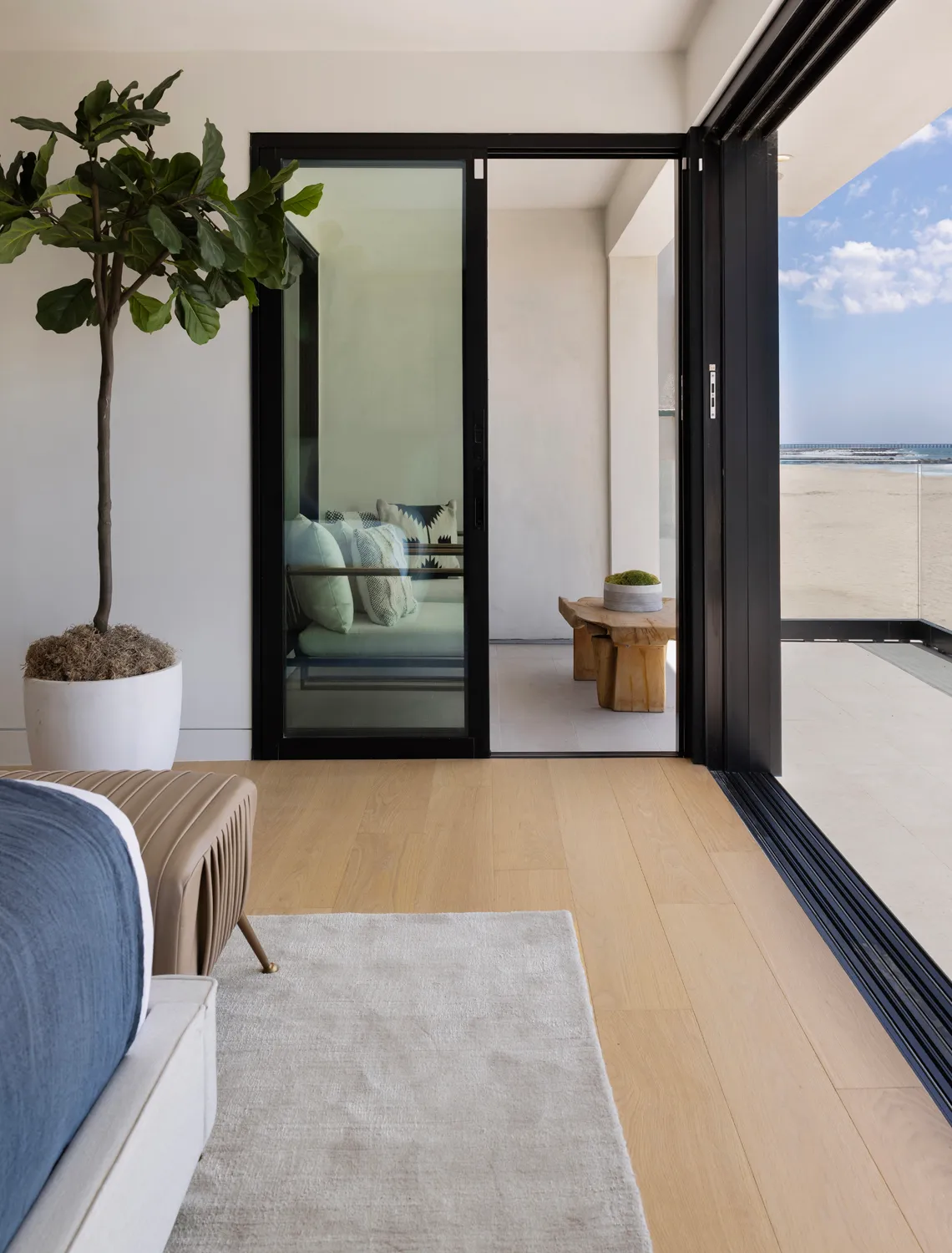 Living room opening to ocean view through black-framed doors
